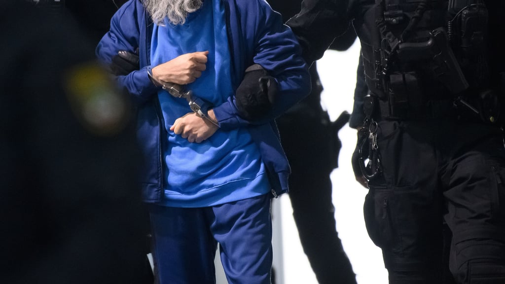 Justizbeamte führen den mit Handschellen gefesselten Angeklagten Taleb A. in das temporäre Gerichtsgebäude des Landgerichts Magdeburg.