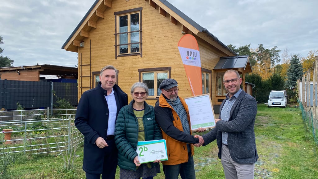 Staatssekretär Thomas Wünsch, Beate und Jörg Radke und Bürgermeister Philipp Stark bei der Auszeichnung mit der Grünen Hausnummer Plus für das Holzhaus.