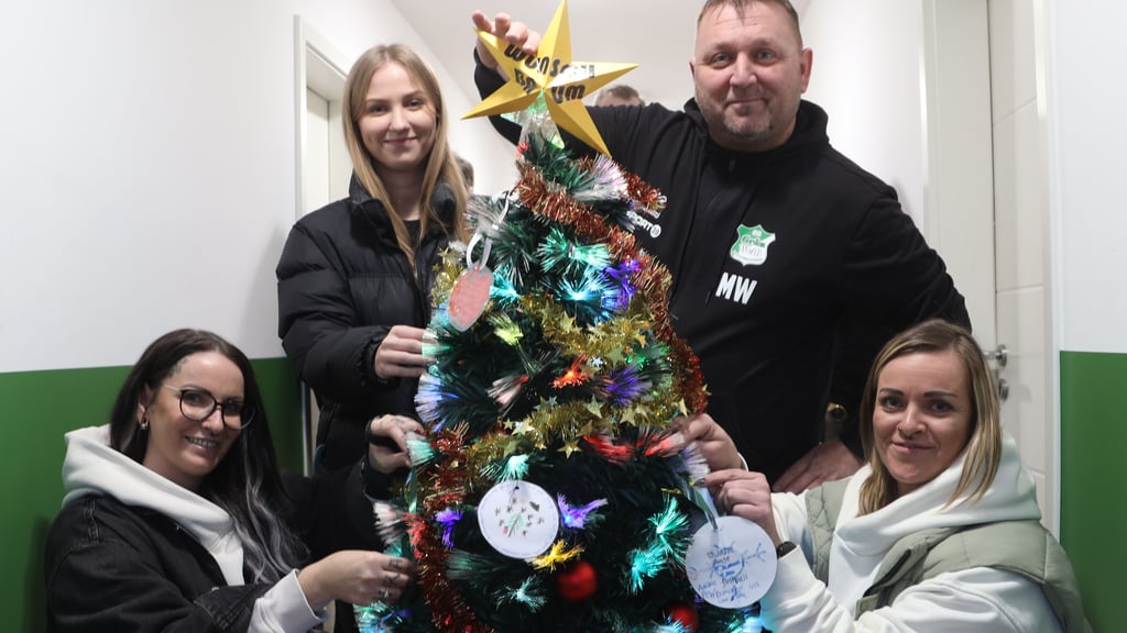 Tina Schulz (links), Romy Wahnschaap und Jenny Pontow (rechts) von der „Kurswechsel Jugendhilfe" in Magdeburg haben mit Marcel Wahnschaap von der SG „Grün Weiß" Dahlenwarsleben den Weihnachtsbaum mit Wünschen bestückt.