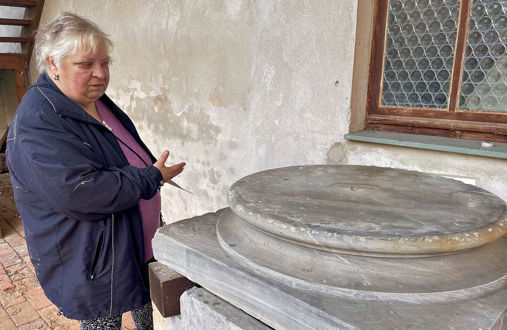 Marlies Kenter vom Heimatverein zeigt auf den Sockel des Grabmals der Anna Ursula Sophie Galster, der an der Westwand des Kirchenschiffs unter der Empore steht. 