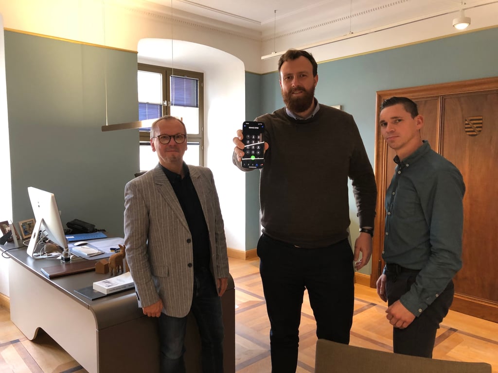 Der Weißenfelser Oberbürgermeister Martin Papke präsentiert mit Sven Hantschel (l.) und Michael Kraft im Rathaus, wie KI-Assistent Charly künftig Fragen von Bürgern am Telefon bearbeitet.