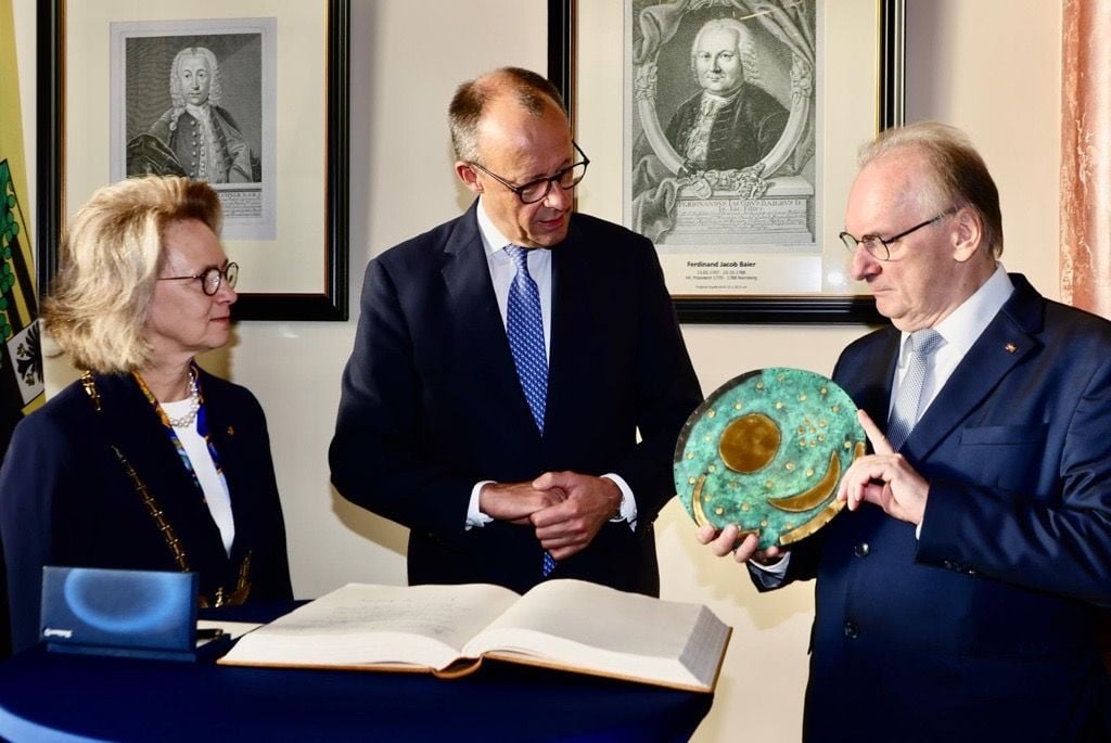 Reiner Haseloff (r.) überreicht Friedrich Merz vor den Augen von Leopodina-Präsidentin Bettina Rockenbach eine Nachbildung der Himmelsscheibe von Nebra.