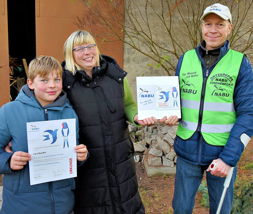 Nadine Randel  und ihr  Sohn  Noah freuen sich über die Auszeichnung „Schwalbenfreundliches Haus“, die Heiko Rasch vom Naturschutzbund in Gnadau-Döben überreichte. 