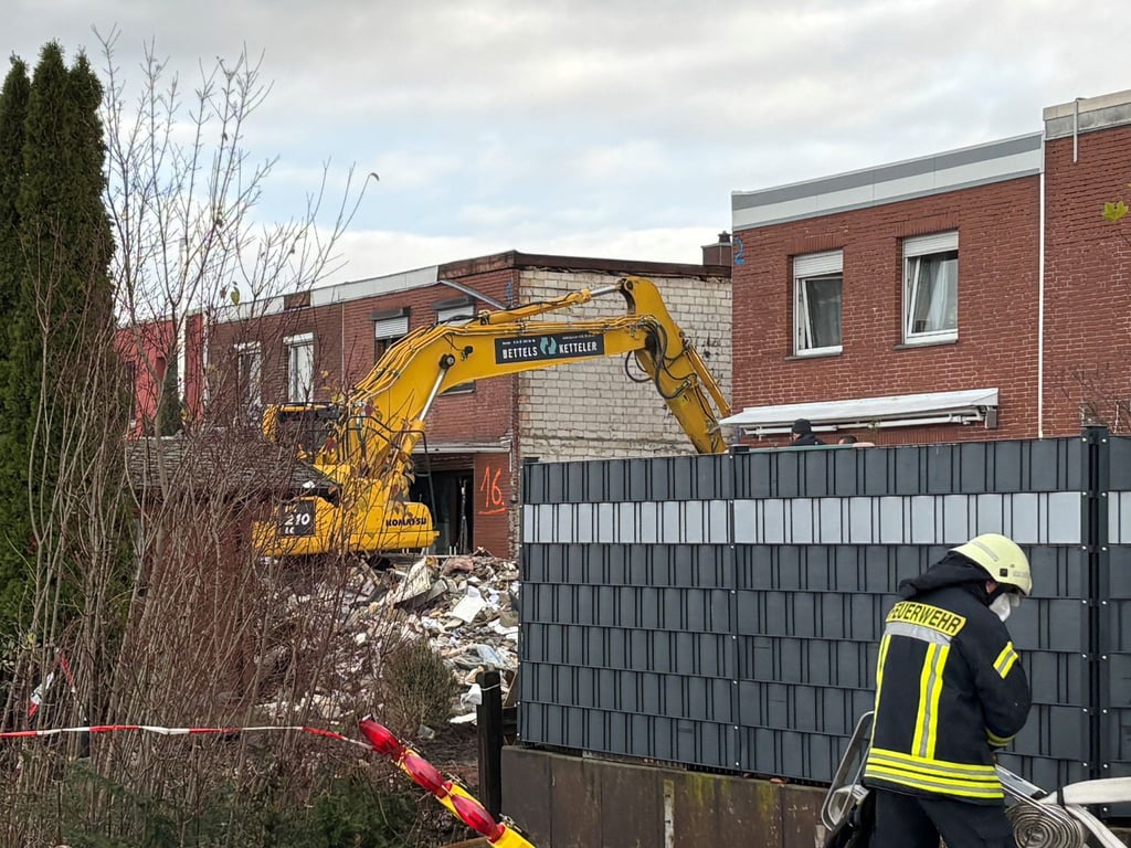 Ein Bagger räumt den Schutt eines eingestürzten Reihenhauses in Wolfenbüttel fort. In den Trümmern ist eine Leiche entdeckt worden.