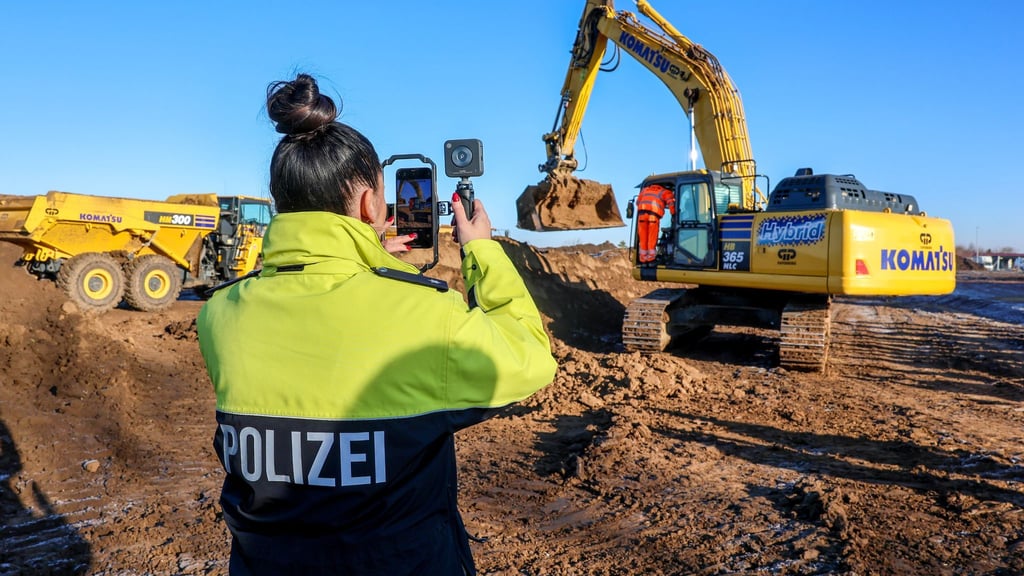 Eine Polizistin filmt einen Bagger beim Spatenstich auf dem Gelände des neuen Landeskriminalamts.