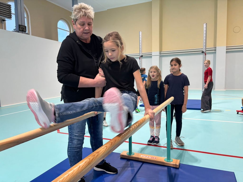 Sportlehrerin Heike Plötz sichert Lucia aus der 2. Klasse der Grundschule „Werner Nolopp“ am Barren in der Turnhalle Berliner Hof in Aken.