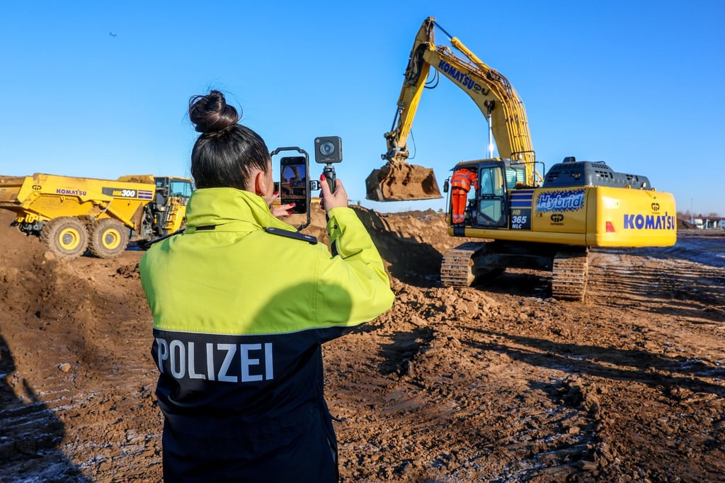 Eine Polizistin filmt einen Bagger beim Spatenstich auf dem Gelände des neuen Landeskriminalamts.
