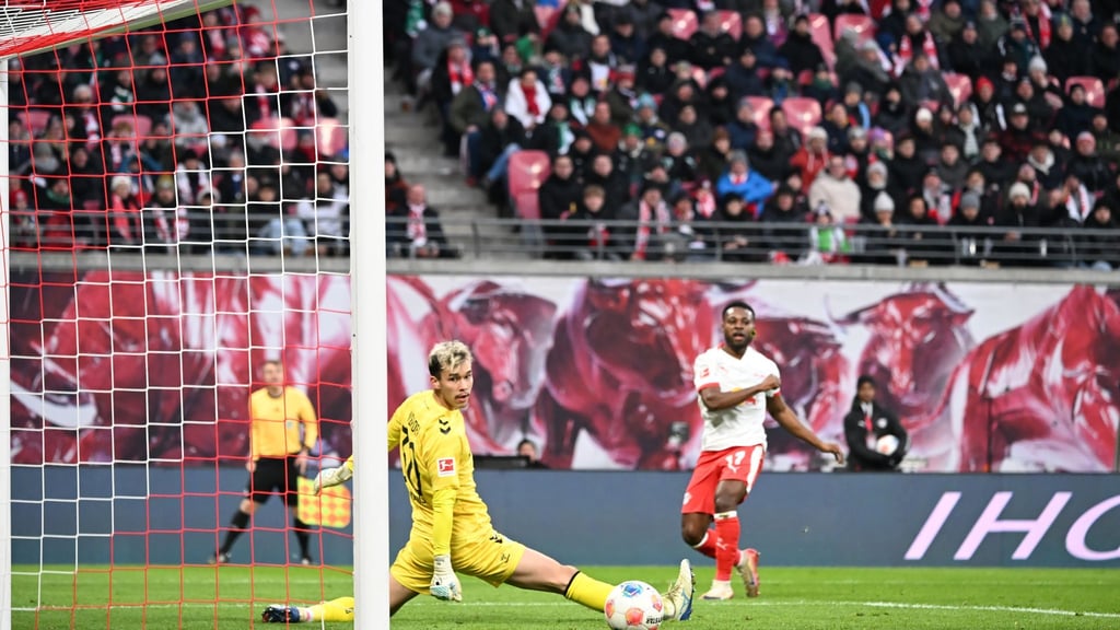 Bremens Torwart Mio Backhaus (l, Werder Bremen) und Ridle Baku (RB Leipzig) schauen dem Ball hinterher. Backhaus verhinderte mit seinen Paraden einen frühen Rückstand der Gäste in Leipzig.