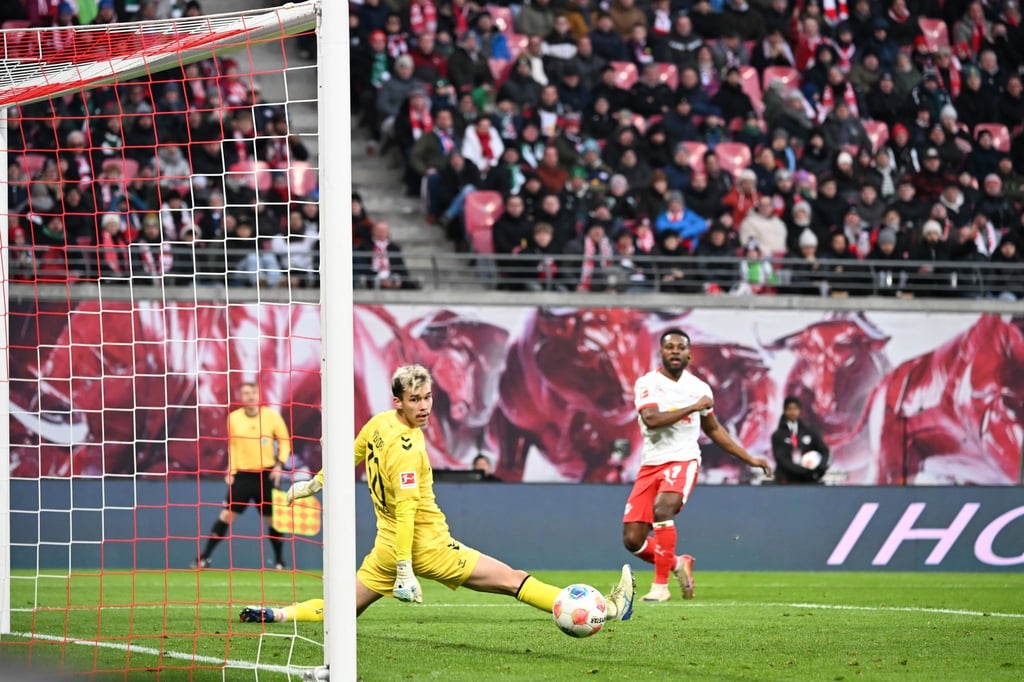Bremens Torwart Mio Backhaus (l, Werder Bremen) und Ridle Baku (RB Leipzig) schauen dem Ball hinterher. Backhaus verhinderte mit seinen Paraden einen frühen Rückstand der Gäste in Leipzig.