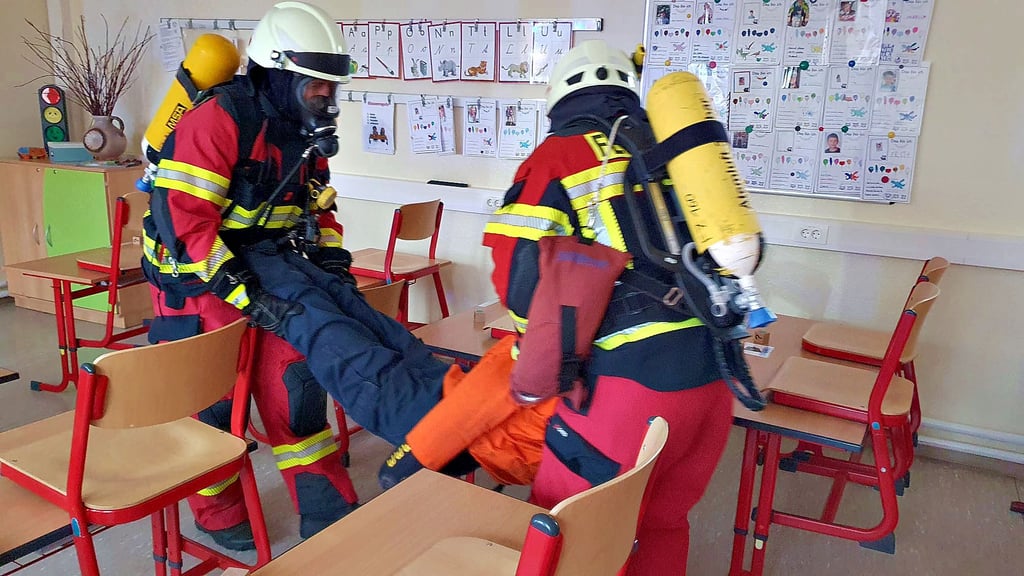 Einer der vermissten Menschen ist gefunden und wird aus dem für die Kamerden  aufgrund einer Folie über dem Gesichtsfeld der Maske stark vernebelten Raum in Sicherheit gebracht.