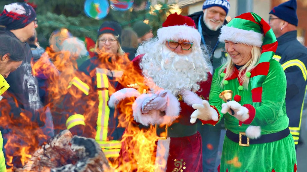 Der Weihnachtsmann und sein Elf wärmen sich am Feuer. 