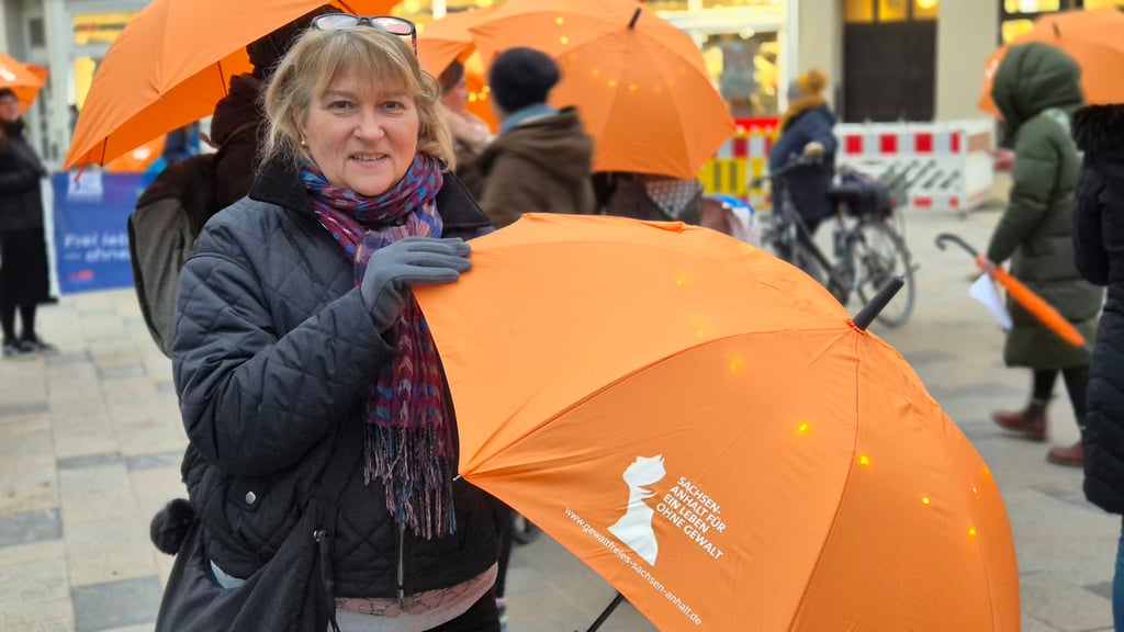 Jacqueline Radtke, Gleichstellungsbeauftragte der Hansestadt Stendal, zeigt einen der Schirme, die an die Teilnehmer des „Orange Walks“ in Stendal verteilt wurden.