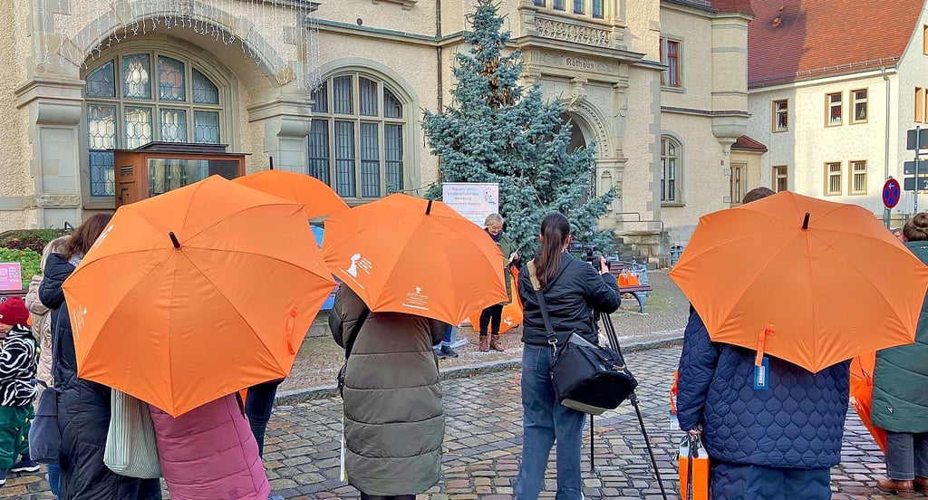Orangefarbene Schirme leuchten anlässlich des Orange Day vor dem Bernburger Rathaus. 