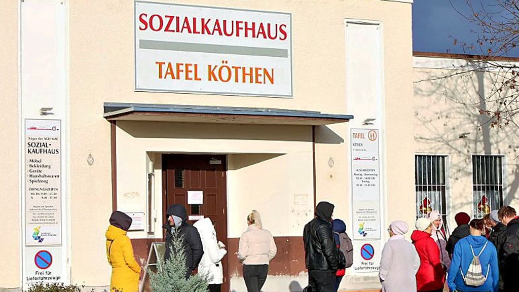 Hilfsbedürftige Menschen warten vorm Eingang der Tafel in Köthen auf deren Öffnung. 