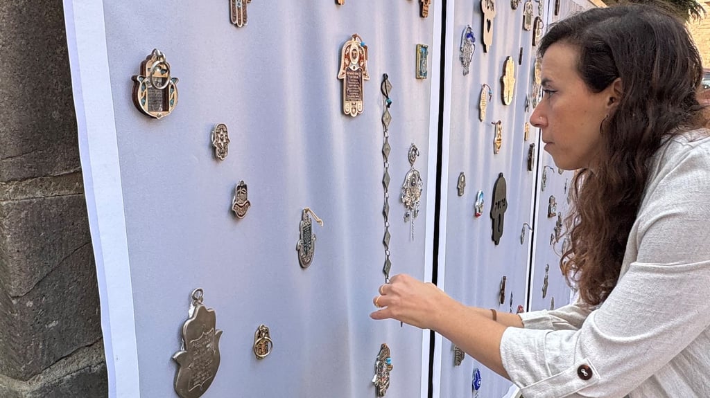 Die Künstlerin Hili Noy befestigt für die Ausstellung „Hamsa“ zahlreiche der schutzbringenden Handsymbole an der Mauer im Hof der Klaus in Halberstadts Rosenwinkel 18. 