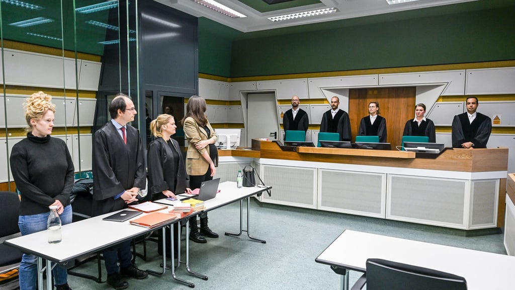 Im Gerichtssaal stehen Anwälte (l) mit der Klägerin und die Richter der 1. Kammer des Verwaltungsgerichts.