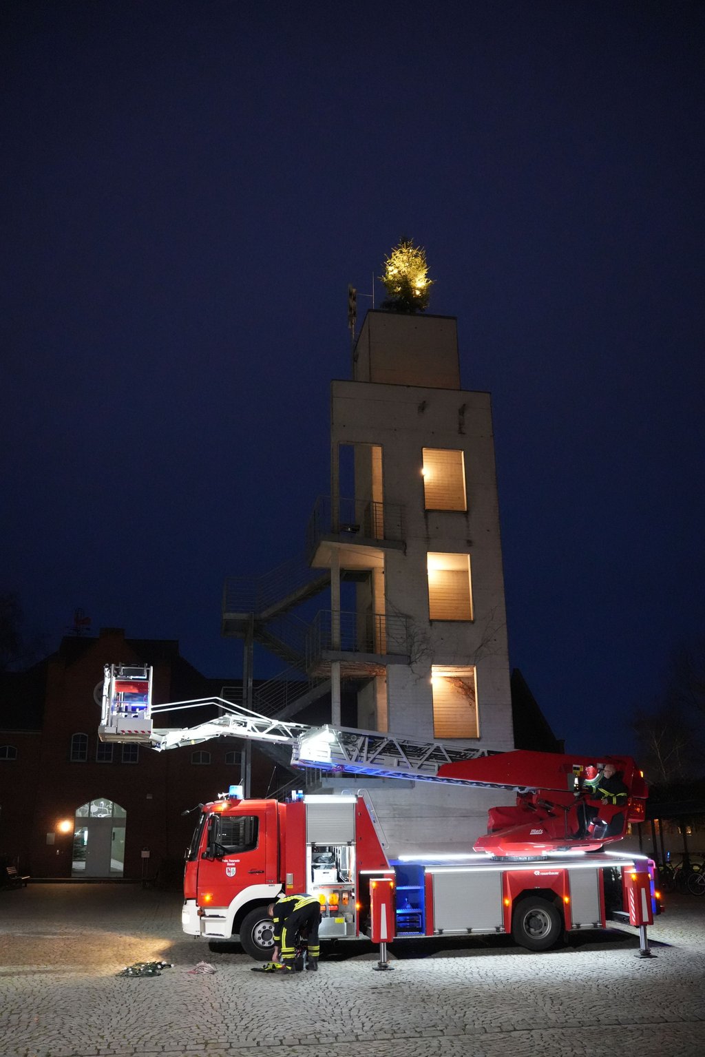 Mit der Drehleiter haben Kameraden der Freiwilligen Feuerwehr Stendal den Weihnachtsbaum auf dem Schlauchturm angebracht.