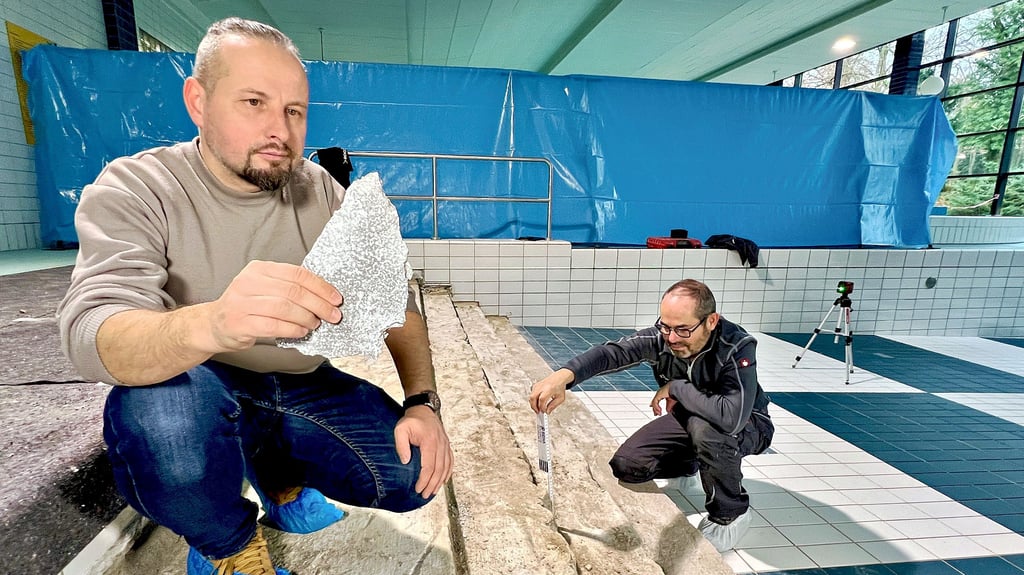 Bereichsleiter Peter Dähne (l.) zeigt die Schäden an der Treppe des Nichtschwimmerbeckens. Fliesenleger  Holger Wustrau hat mit der Sanierung begonnen. 