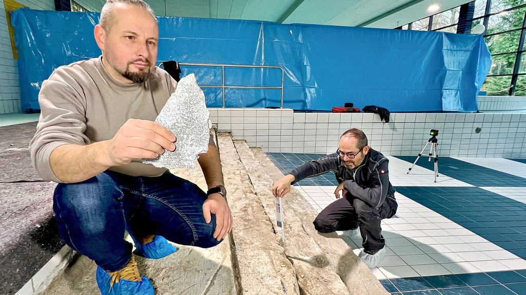 Bereichsleiter Peter Dähne (l.) zeigt die Schäden an der Treppe des Nichtschwimmerbeckens. Fliesenleger  Holger Wustrau hat mit der Sanierung begonnen. 