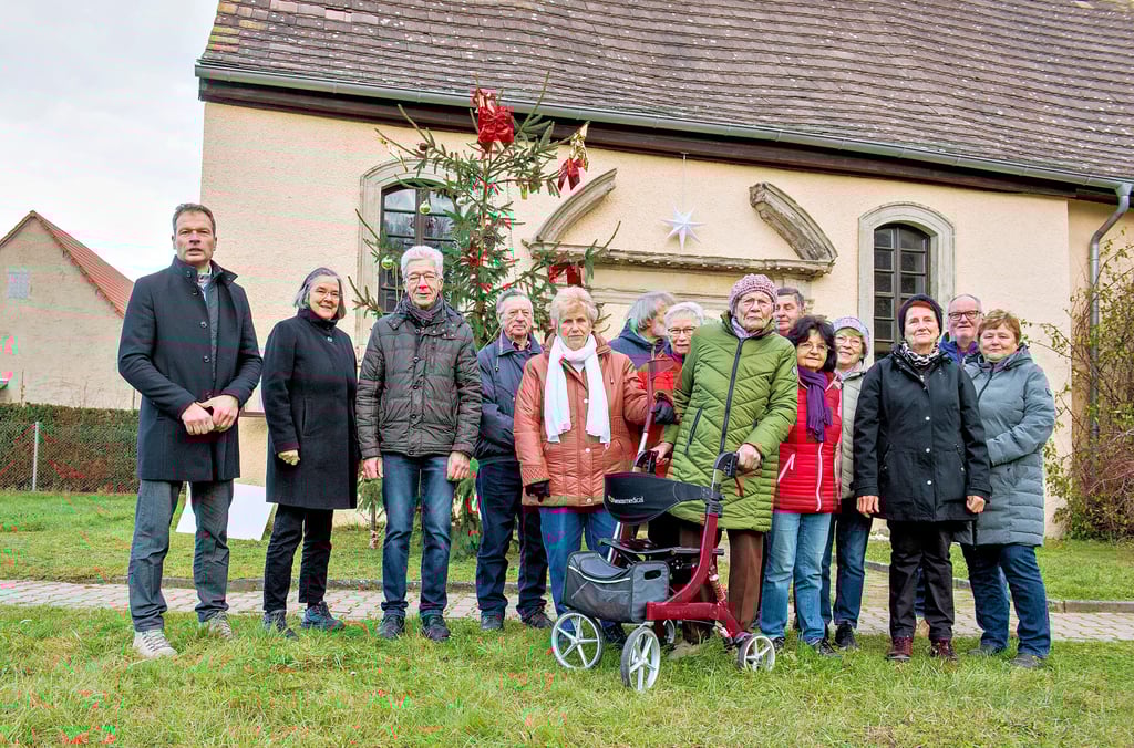 Zur Fördermittelübergabe an der Tröbsdorfer Kirche sind neben Vertretern der Kirchengemeinde auch einige  Einwohner zugegen.  