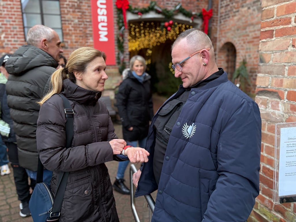 Security-Mitarbeiter Sebastian Schmundt ist beim Adventsmarkt im Kloster Jerichow im Einsatz. Hier zeigt ihm Besucherin Jana Schulz ihr Eintrittsbändchen. 