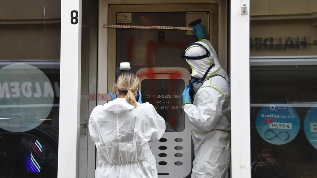 Kriminaltechniker vermessen und fotografieren das verfassungswidrige Symbol an der Geschäftstür des Handyladens in der Hagenstraße in Haldensleben.