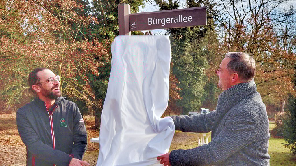 Silvio Merkwitz (links), Vorsitzender des Verschönerungsvereins,   und Ascherslebens OB Steffen Amme enthüllen das „Straßenschild“ für die Bürgerallee.