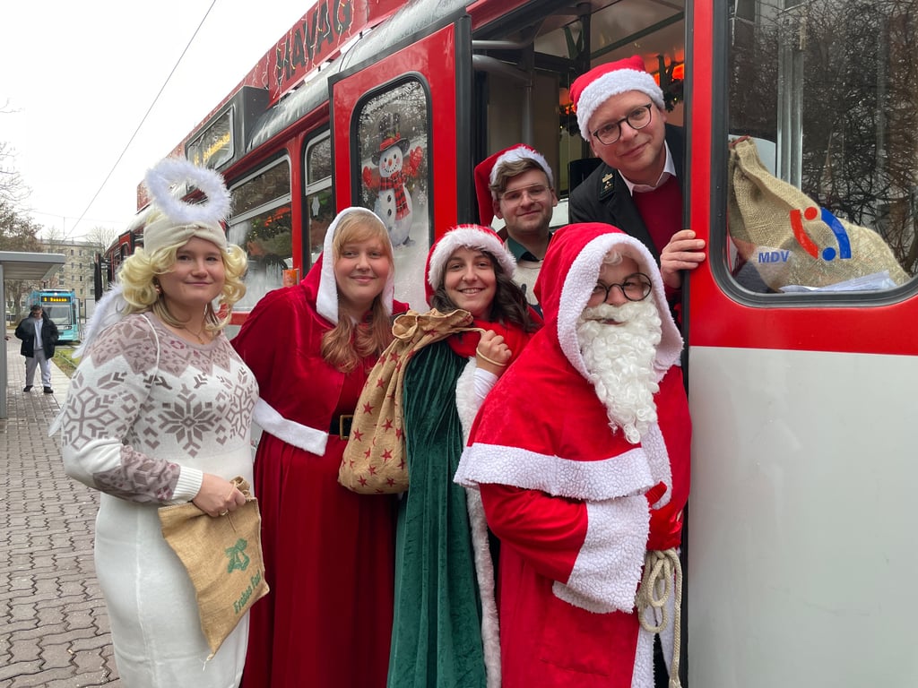 Laden in die Adventsbahn ein: Jacqueline Matheis als Engel (v.l.), Saskia Lochmann, Ulrike Korn, Weihnachtsmann Philipp Hackemesser und die Fahrer André-Maximilian Würz und Christoph Sawatzki von den „Halleschen Straßenbahnfreunden“.