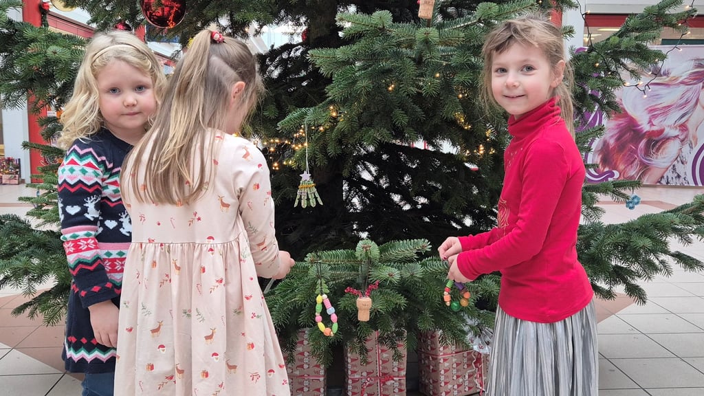 Melina (v.l.), Emilia und Anastasia aus der Kita Regenbogen hängen ihren selbstgebastelten Schmuck an den Baum.