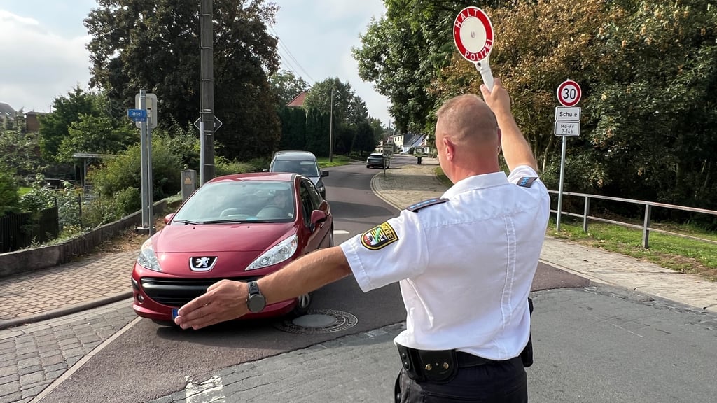 Ein Polizist winkt bei einer Kontrolle ein Fahrzeug an den Rand.