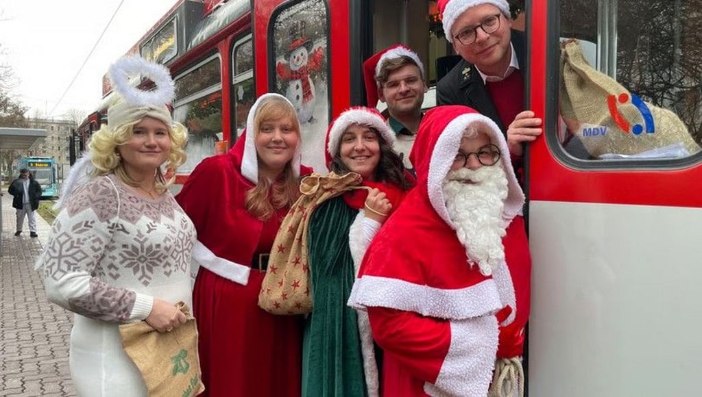 Laden in die Adventsbahn ein: Jacqueline Matheis als Engel (v.l.), Saskia Lochmann, Ulrike Korn, Weihnachtsmann Philipp Hackemesser und die Fahrer André-Maximilian Würz und Christoph Sawatzki von den „Halleschen Straßenbahnfreunden“.