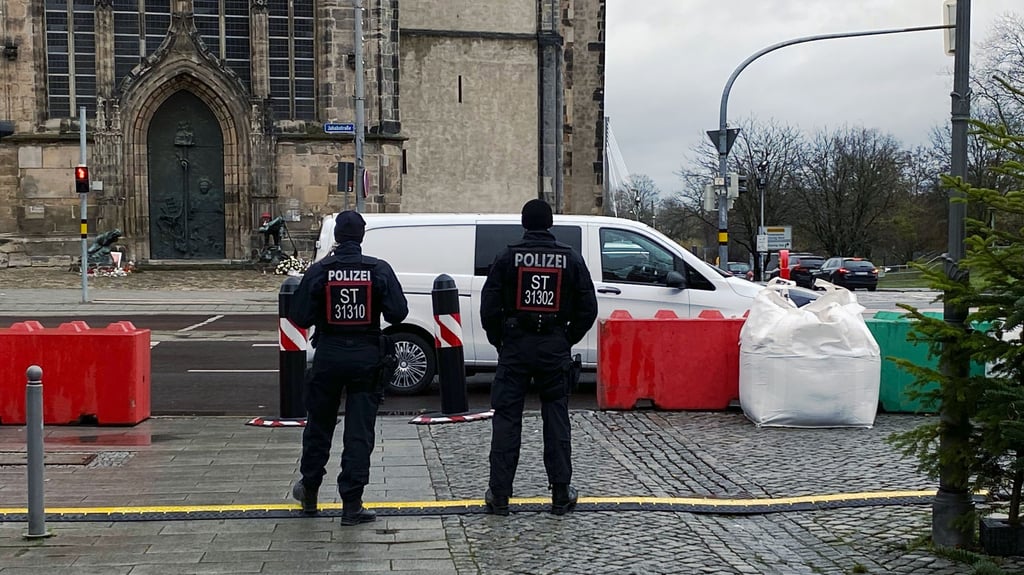 Zwei Polizisten sichern gegenüber der Johanniskirche den Eingang zum Magdeburger Weihnachtsmarkt ab. Der Alte Markt ist festungsgleich gesichert – doch für kleine Stadtteilmärkte fehlt es weiter an klaren Regeln.