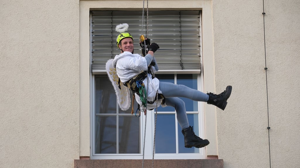 Ein Kamerad der Höhenrettung der Chemnitzer Feuerwehr seilt sich im Weihnachtsengel-Kostüm an der Fassade des Klinikums Chemnitz ab.