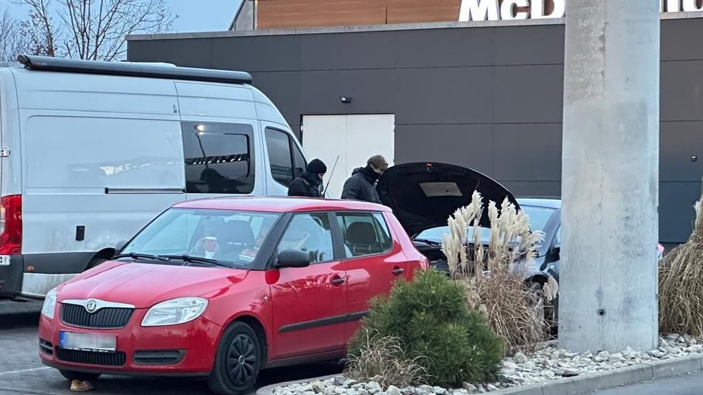 Auf dem Foto sind vermummte Polizeibeamte zu sehen, die auf dem Autohof nahe des Mc-Donald's-Restaurants ein Auto kontrollieren.