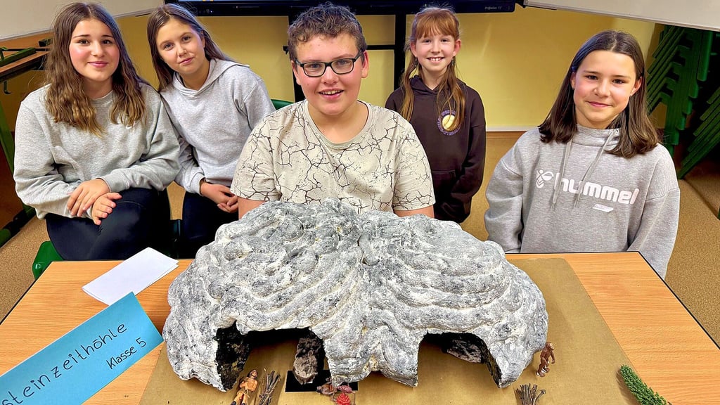 Anton Smirat (Mitte) präsentiert seine selbstgebaute Altsteinzeithöhle.  Für die  Erledigung  dieser  freiwilligen Hausaufgabe hat der Sekundarschüler  die  Note  eins erhalten.