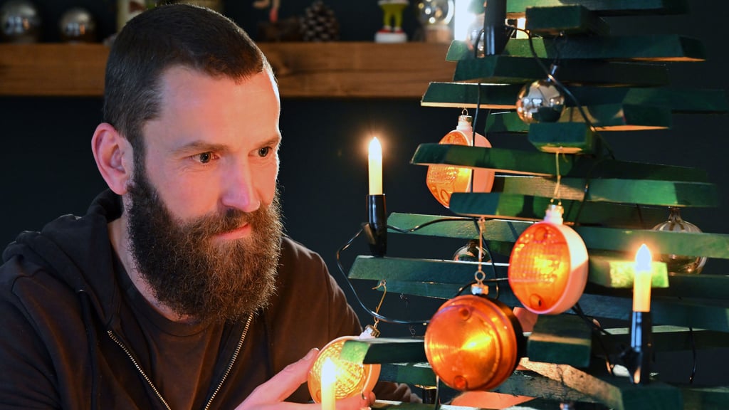Jan Hofmann schmückt einen Weihnachtsbaum mit Weihnachtsbaumkugeln aus Simson-Blinkern.