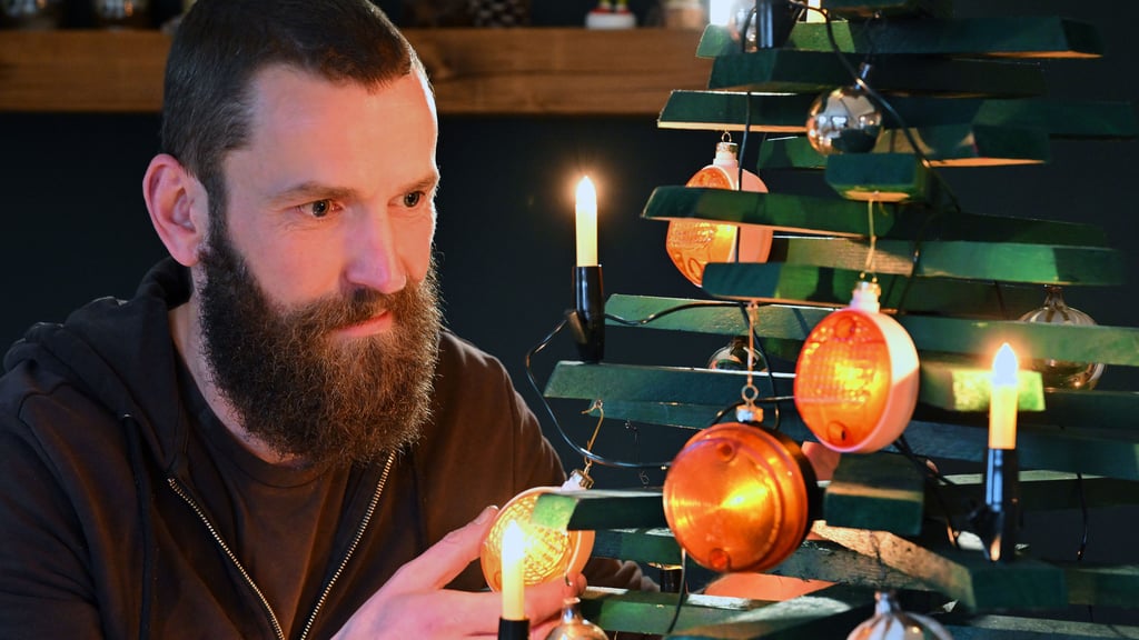 Jan Hofmann schmückt einen Weihnachtsbaum mit Weihnachtsbaumkugeln aus Simson-Blinkern.