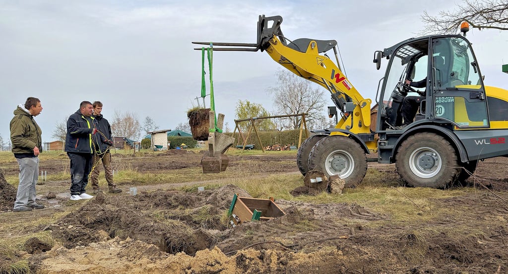 Marcus Höhne (3. von links) und Daniel Eichbaum (im Bagger) reißen die Stützen der Sitzbänke im früheren Sinnesgarten am Chausseehaus Hassel aus dem Erdreich.