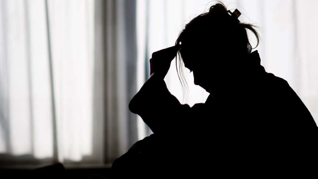 Silhouette einer Frau vor einer hellen Fensterfront