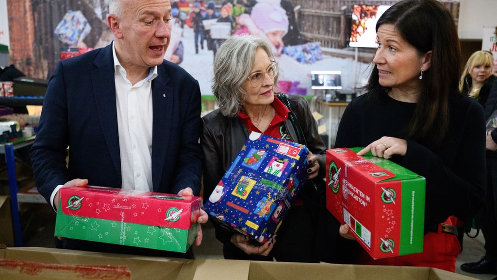 Berlins Regierender Bürgermeister Kai Wegner und Bildungssenatorin Katharina Günther-Wünsch (ganz rechts) machen sich ein Bild von der Aktion „Weihnachten im Schuhkarton“.