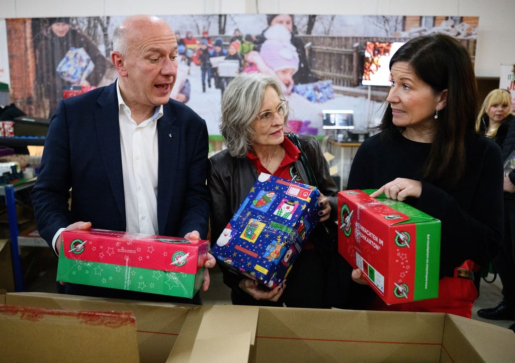 Berlins Regierender Bürgermeister Kai Wegner und Bildungssenatorin Katharina Günther-Wünsch (ganz rechts) machen sich ein Bild von der Aktion „Weihnachten im Schuhkarton“.