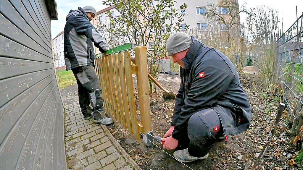 Mitarbeiter der Firma Schagow Bau aus Ermsleben setzen einen neuen Zaun im Außenbereich der Kita „Fröbels Spielkiste“.
