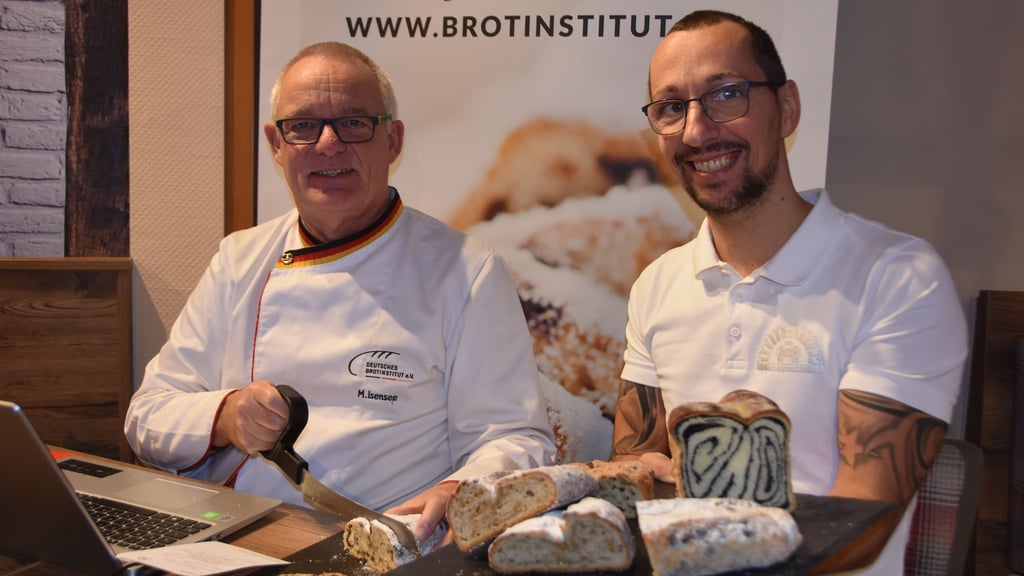 Michael Isensee (l.) schneidet sich ein Stück Stollen ab, während Bäckermeister Denni Nitzschke daneben sitzt und das Werk seines Teams stolz betrachtet.