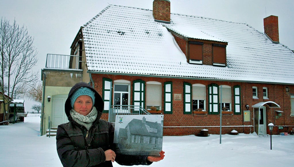 Heimatvereinsvorsitzende Aileen Lemme mit einer historischen Aufnahme des einstigen Schulgebäudes, heute Haus der Vereine . 
