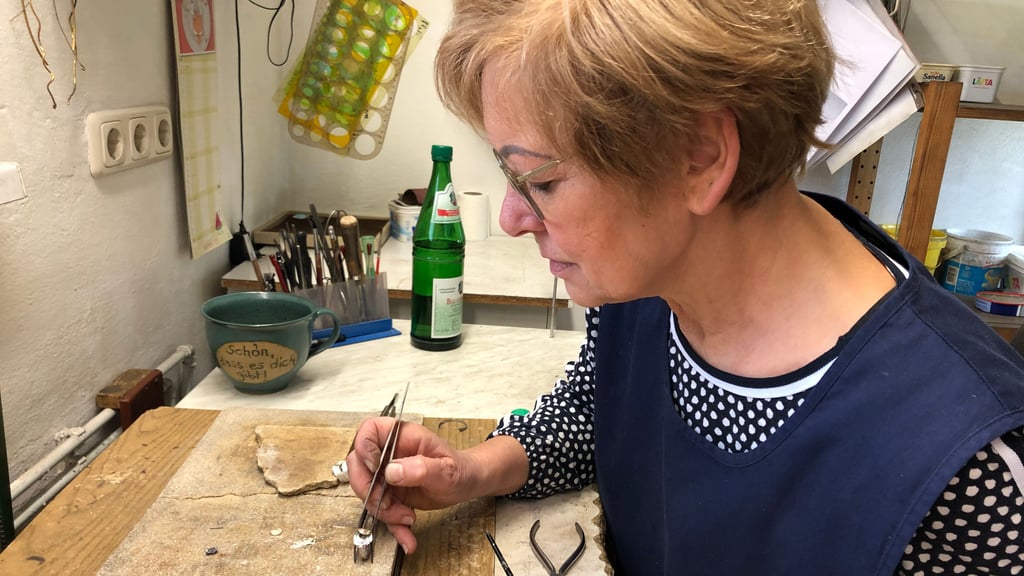 Schmuckgürtlerin Anke Winter, die seit 1991 im Unternehmen mitarbeitet, setzt eine kleine Himmelsscheibennachbildung auf den Ring auf, den sie zuvor aus Silberblech geformt hat.