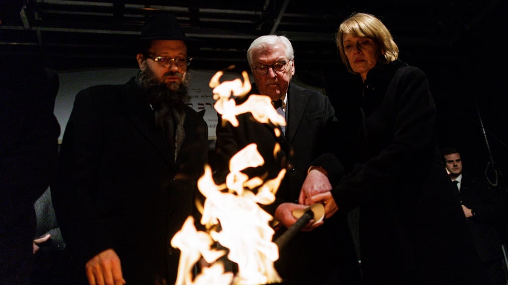 Stunden nach dem brutalen Anschlag in Sydney zündeten Rabbiner Yehuda Teichtal (l), Bundespräsident Frank-Walter Steinmeier und seine Frau Elke Büdenbender gemeinsam eine Fackel für die erste Kerze des Chanukka-Leuchters vor dem Brandenburg Tor an.
