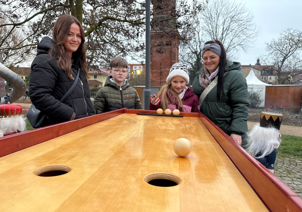 Nicole Enge (von links), Mats und Lina und Lisa Bukowski vergnügen sich an einem der Geschicklichkeitsspiele, die bei der Altstadtweihnacht am Weinberg in Burg ausprobiert werden können.