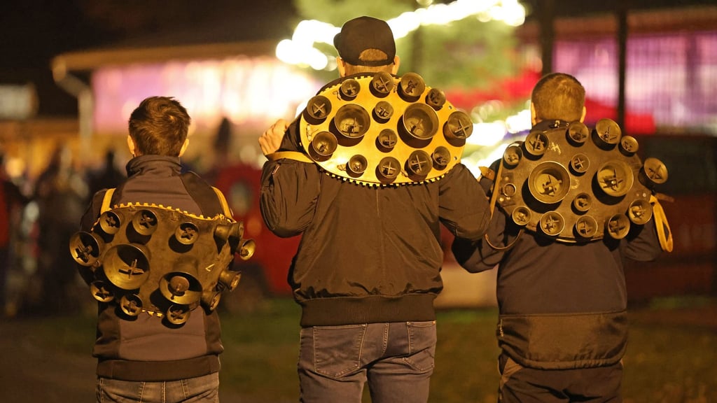 Drei Mitglieder der Brauchtumsgruppe Weihnachtsmänner e.V. stehen mit Schellengeläut auf dem Weihnachtsmarkt in Altenbrak. Am ersten Feiertag ziehen sie in kompletter Dunkelheit durch den Ort.
