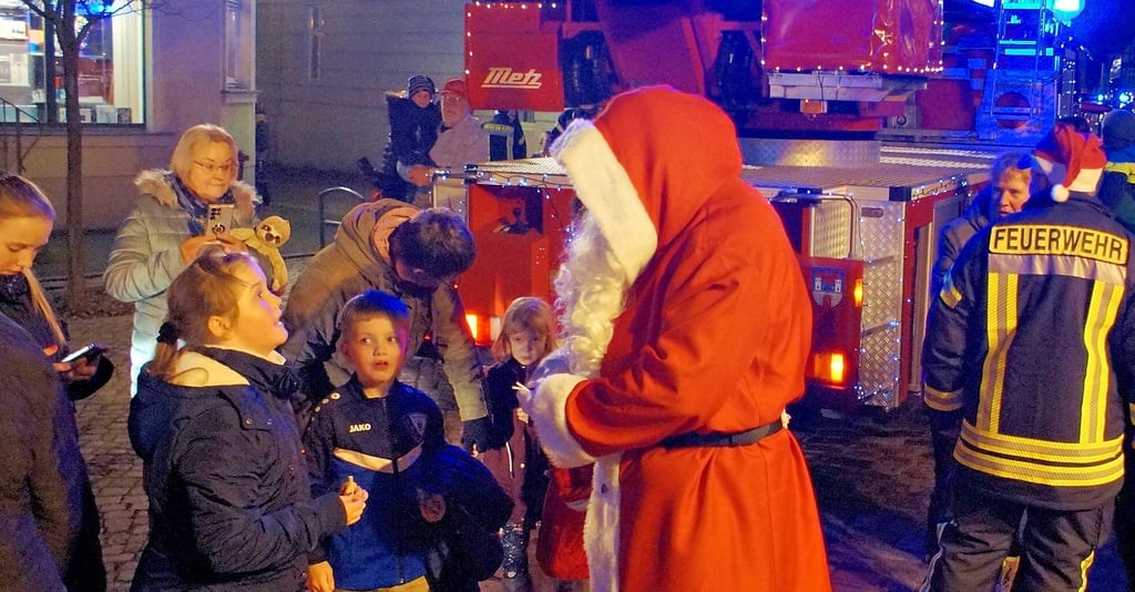 An den einzelnen Stationen der Lichterfahrt der Feuerwehr Havelberg verteilte der Weihnachtsmann so wie hier auf dem Marktplatz Süßigkeiten an die Kleinsten und es wurden viele Fotos gemacht. 