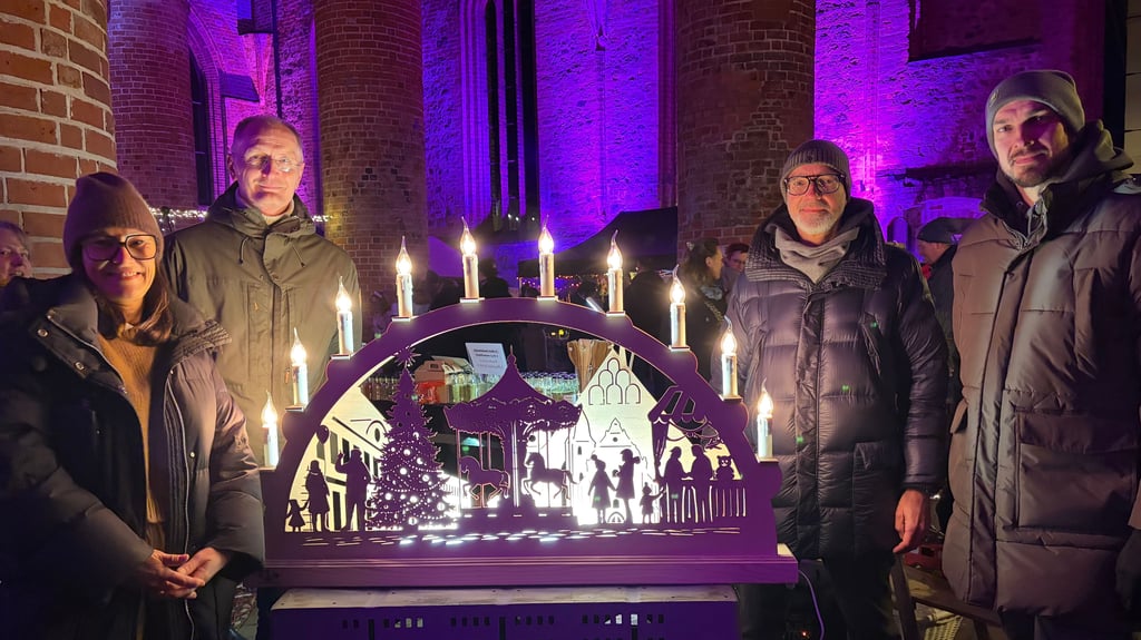 Anne-Kathrin Poßekel (l.) und ihr Partner Joachim Scholtz (2.v.r.) werden den Schwibbogen, den der Zerbster Robert Willno (r.) gefertigt hat, bei sich zu Hause aufstellen.